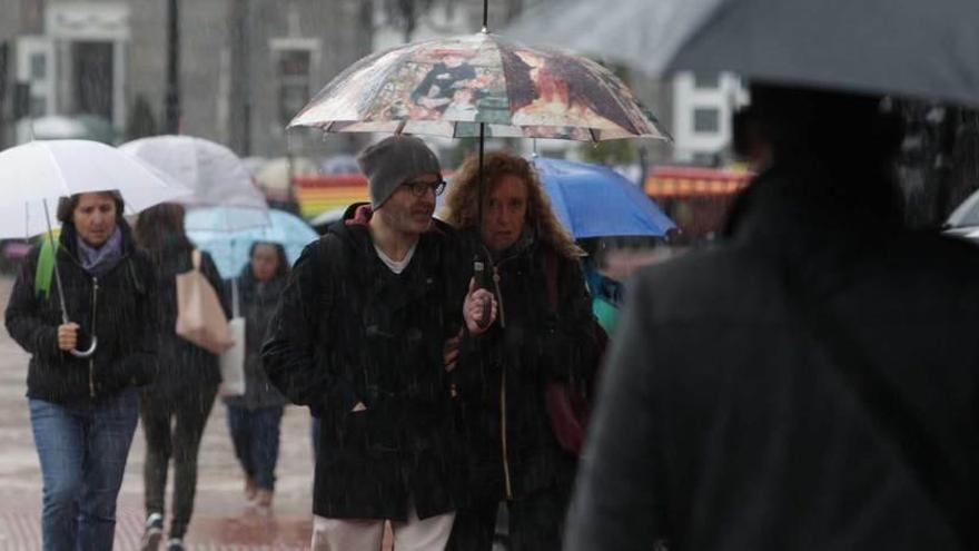 Vecinos de Oviedo, ayer, con paraguas.