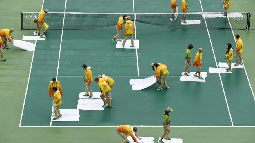 Operarios secan la pista central con toallas.