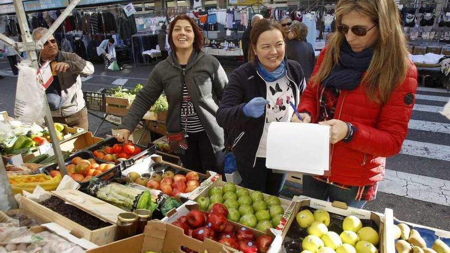 Un momento de la recogida de firmas entre feriantes y clientes en el mercadillo de esta semana.  // Jose Lores