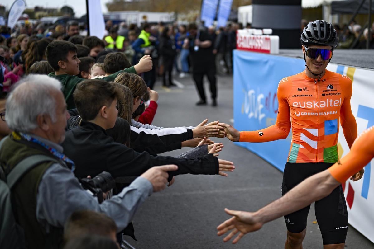 Un integrante del equipo Euskaltel Euskadi da la mano a los niños aficionados desplazados hasta Benicassim