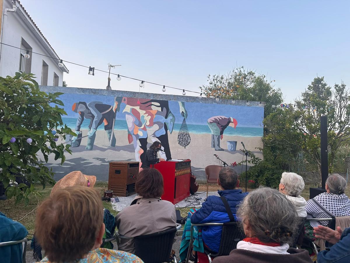 Concerto no xardín de Uxía co mural de Xurxo Romero de fondo adicado ás sequeiras, ás mariscadoras.