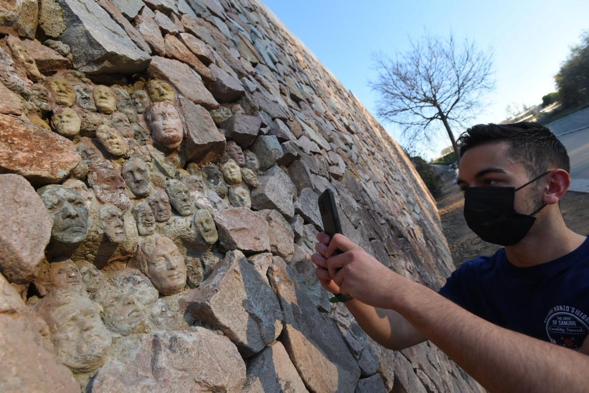 Un joven hace una foto a las caras instaladas entre las piedras.
