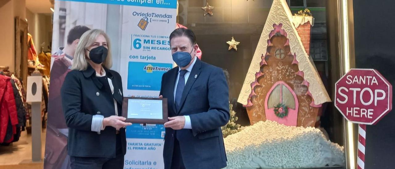 Canteli, a la derecha, entregando el primer premio del concurso de escaparates a Maribel Menéndez delante de su tienda de moda de la calle Posada Herrera. | LNE