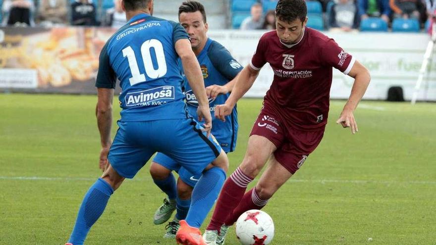 Kevin conduce el balón mientras trata de deshacerse de la presión de dos jugadores rivales durante el encuentro del sábado frente al Club de Fútbol Fuenlabrada. // Área 11