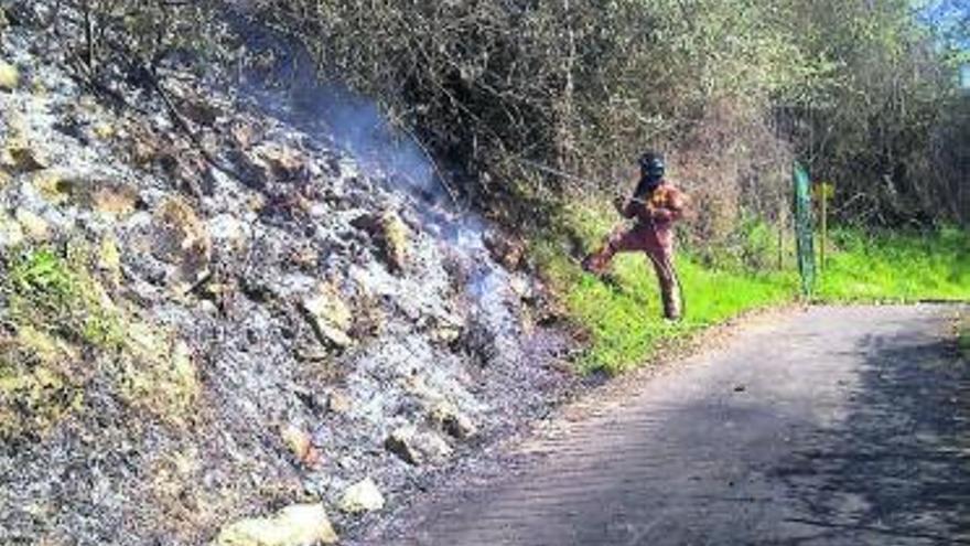 Un bombero apaga el fuego, en La Acebera.