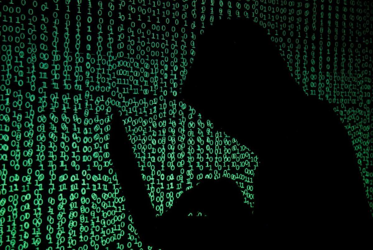 A hooded man holds a laptop computer as cyber code is projected on him in this illustration picture taken on May 13  2017  Capitalizing on spying tools believed to have been developed by the U S  National Security Agency  hackers staged a cyber assault with a self-spreading malware that has infected tens of thousands of computers in nearly 100 countries  REUTERS Kacper Pempel Illustration