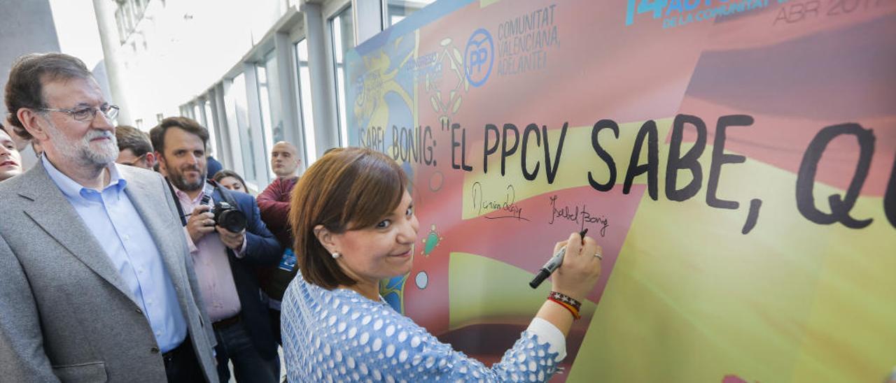 La presidenta regional Isabel Bonig, firma en la «senyera» ante Mariano Rajoy.