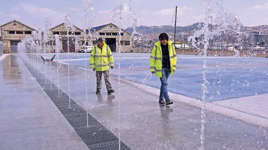 Dos operarios supervisan ayer los surtidores instalados en la explanada de la Estación Marítima.  // Marta G. Brea