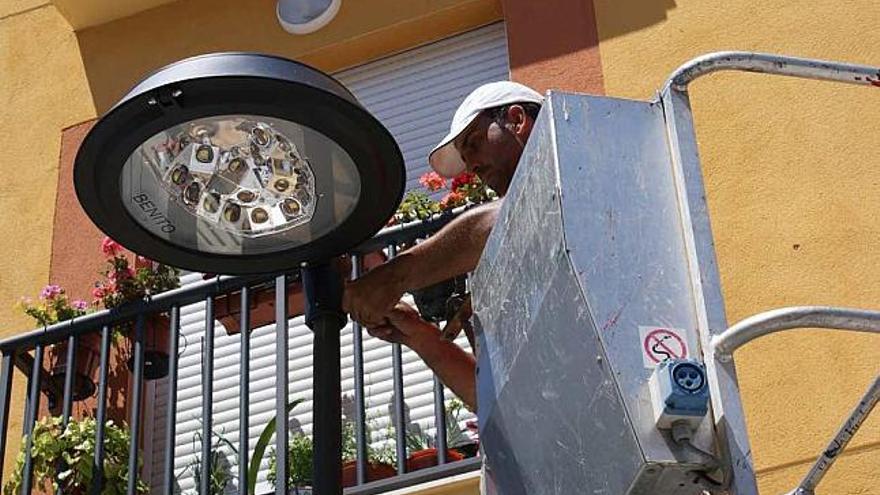 Un operario cambia una bombilla antigua por otra LED de bajo consumo en una farola.