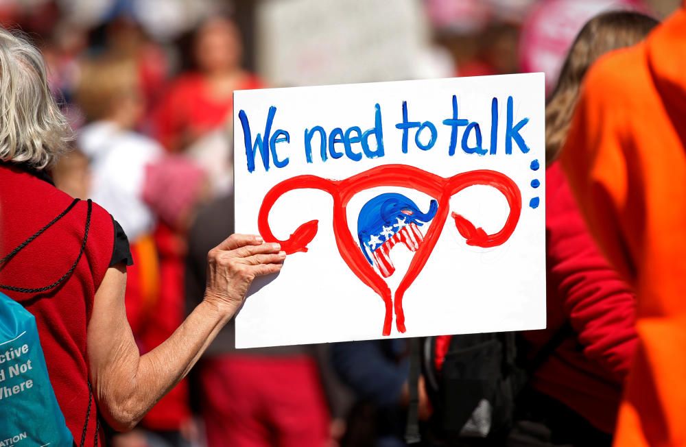 A protester holds a sign aloft as she and ...