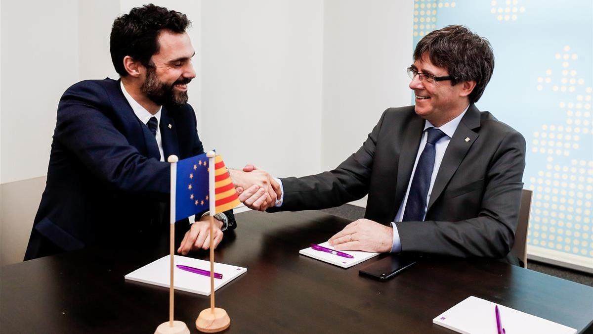 El expresidente de la Generalitat Carles Puigdemont estrecha la mano del presidente del Parlament, Roger Torrent.