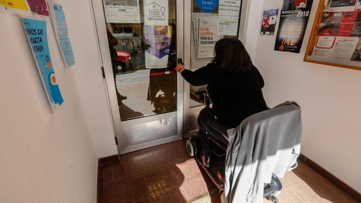 Una mujer en silla de ruedas entrando a un centro social de Elche.