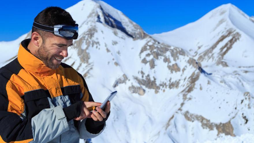 Un esquiador consulta su teléfono móvil.