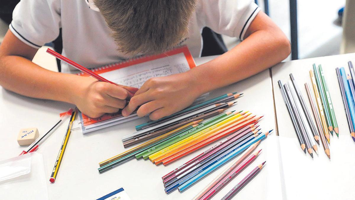 Un niño colorea una libreta en el inicio de curso en un colegio.