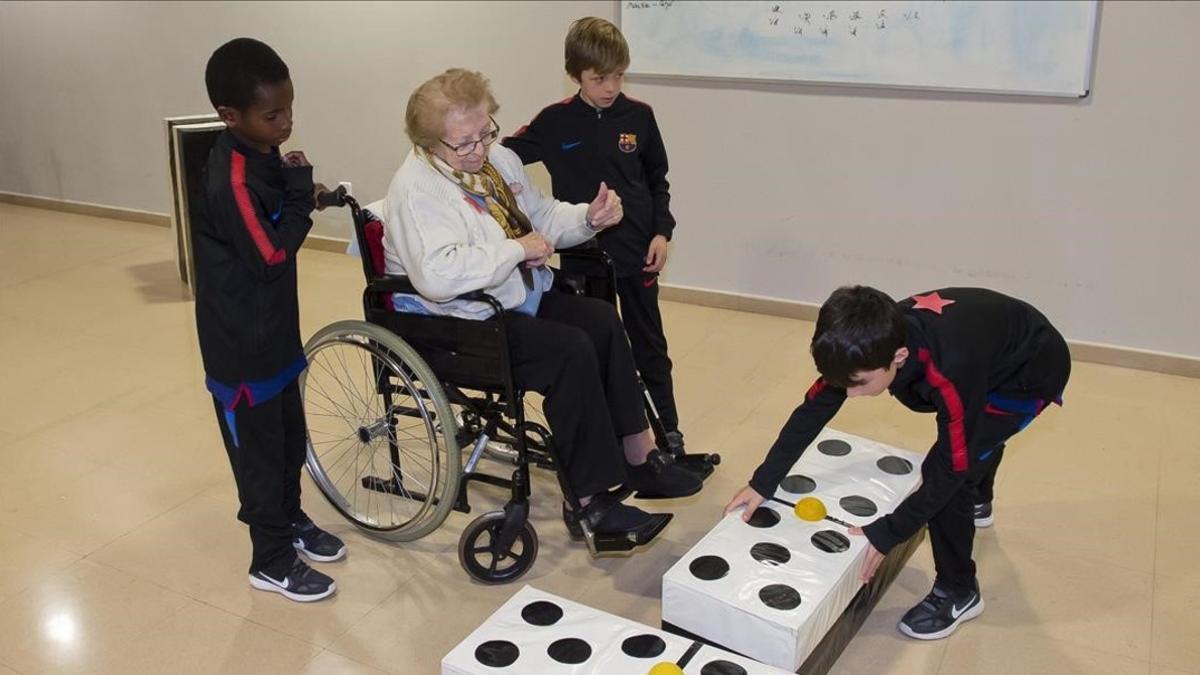 Niños de la cantera del Barça juegan al dominó con abuelos de la residencia Blau Almeda, de Cornellà.