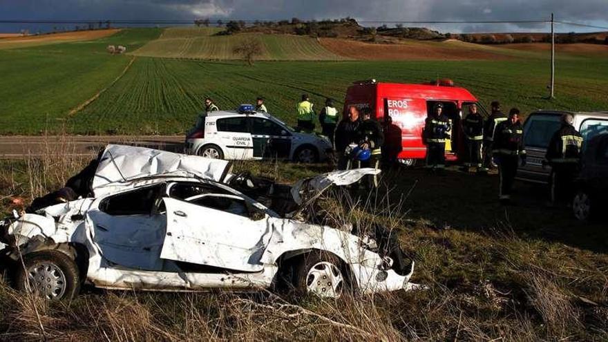 En primer plano, el vehículo siniestrado y al fondo la Guardia Civil, Bomberos de Toro y el coche funerario que trasladó los cuerpos sin vida.