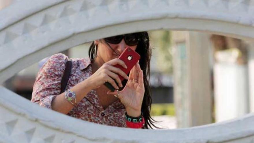 Una joven juega con su teléfono móvil.