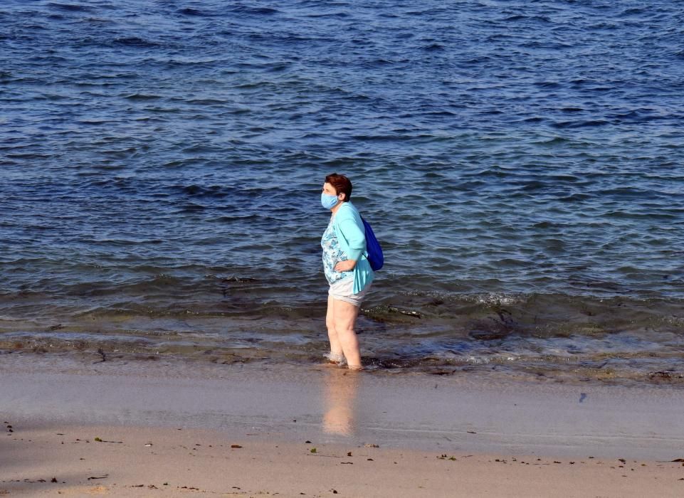 Los coruñeses que se acercan a las playas cumplen con la obligación de usar la mascarilla salvo para entrar en el agua.