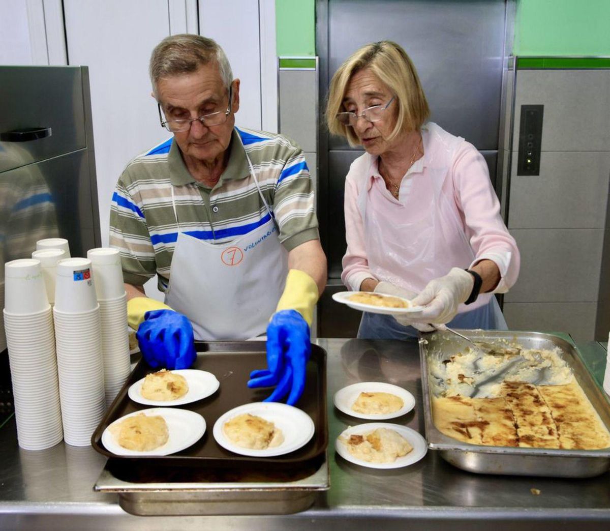 Voluntarios de la Cocina Económica de Gijón sirviendo ayer raciones de comida.