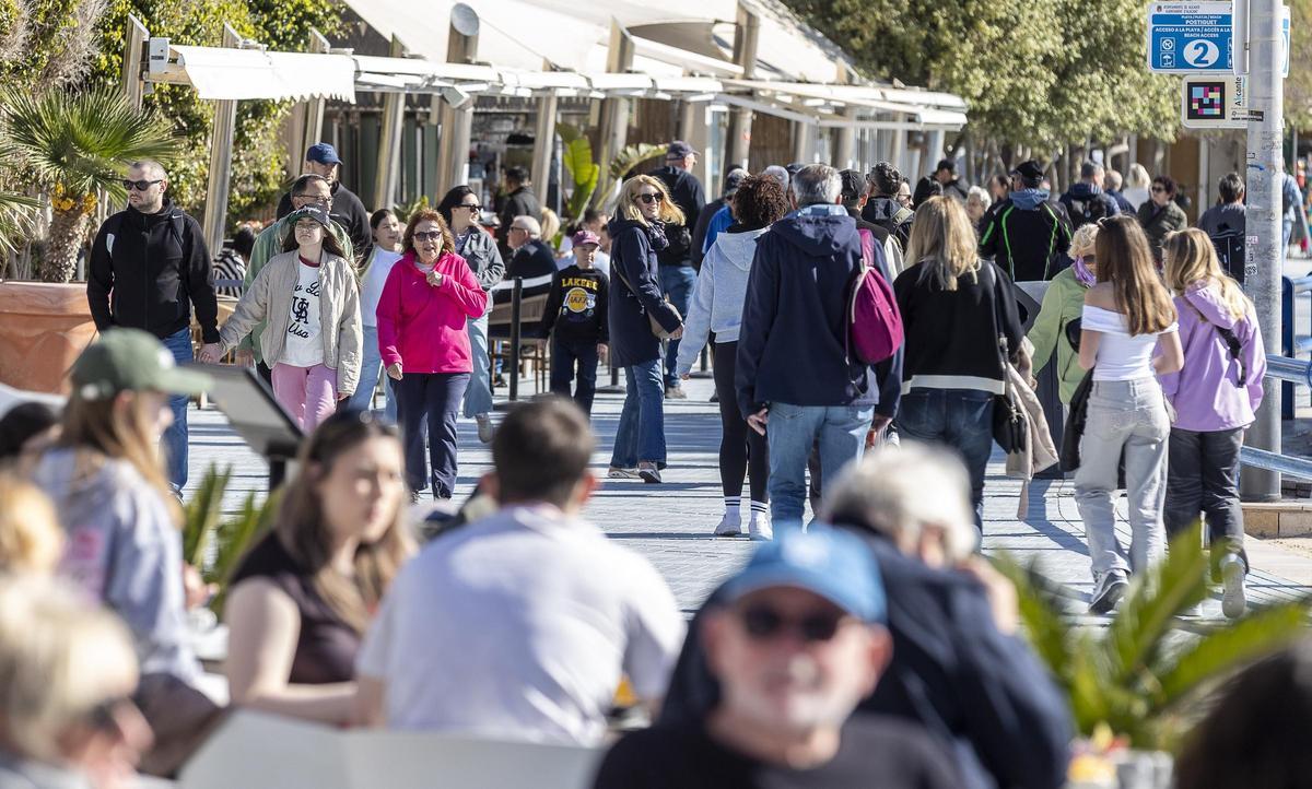 Turistas transitando por Alicante junto a terrazas de bares totalmente llenas.