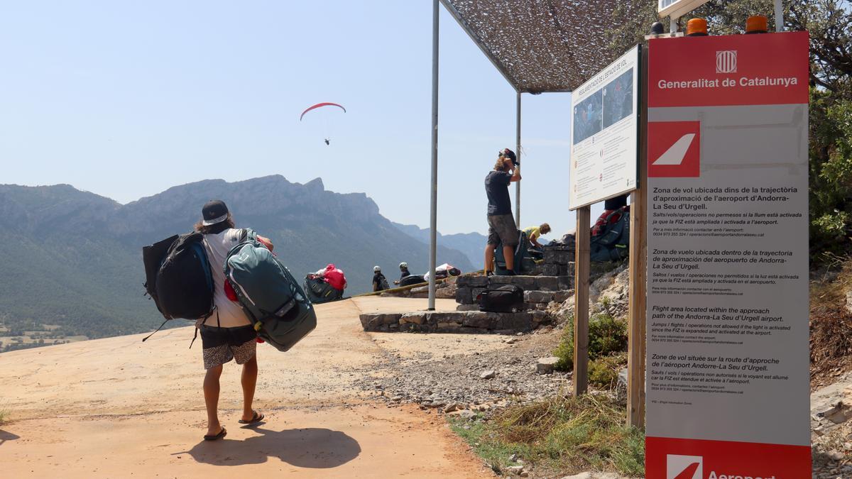 El tòtem d&#039;Aeroports de Catalunya amb els llums apagats, fet que indica que es pot volar en parapent a la zona d&#039;envol d&#039;Organyà i on es veu una persona arribant i un parapent volant al fons