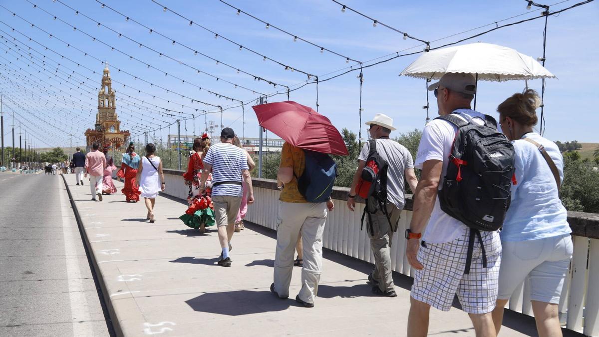 Visitantes de la Feria de Córdoba se protegen del calor con un paraguas.