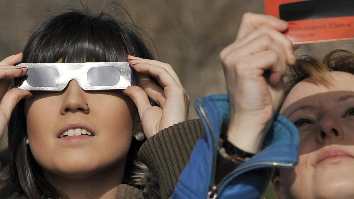 Dos mujeres observan un eclipse solar.