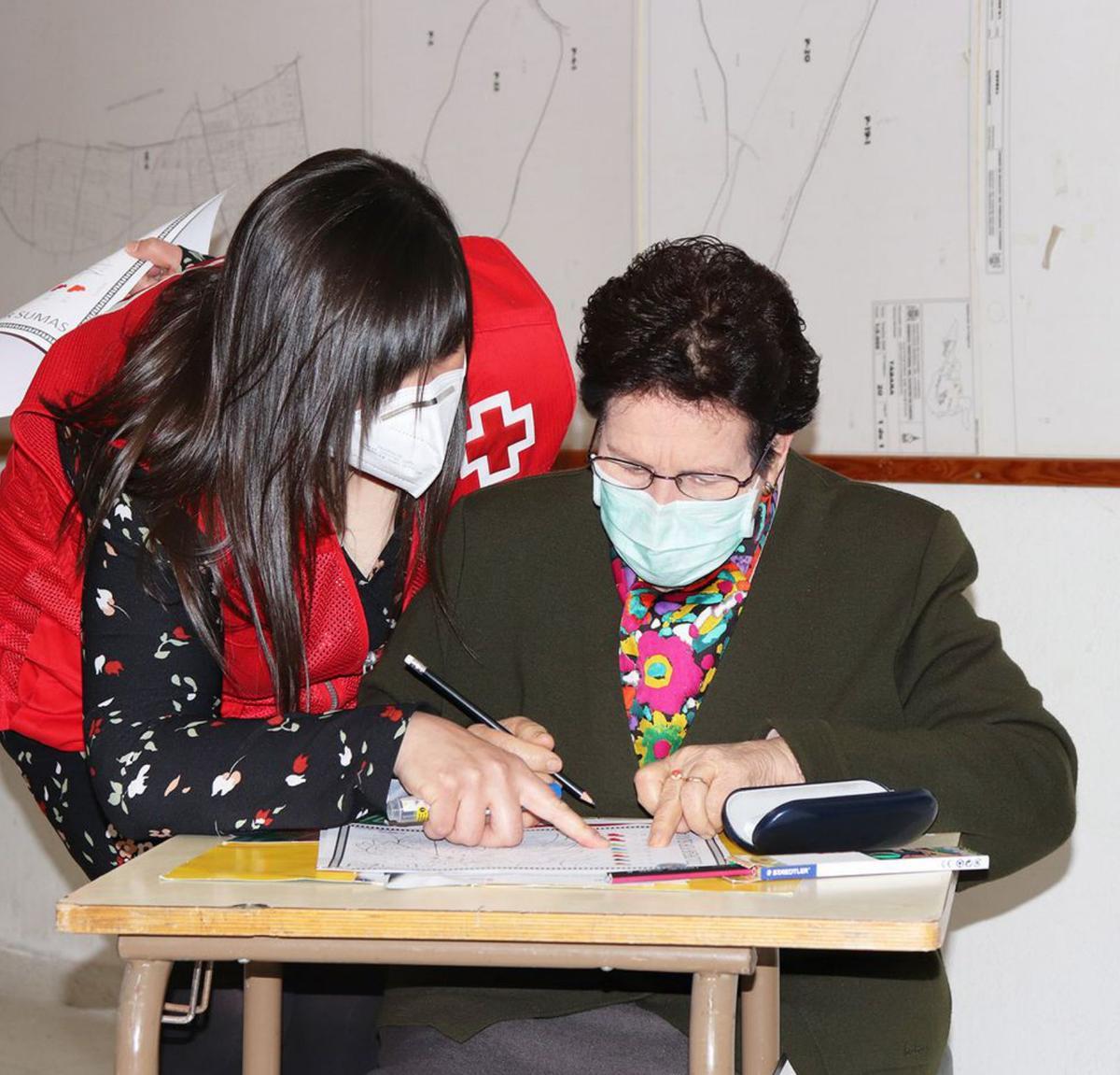 Una trabajadora de Cruz Roja ayuda a una usuaria en un taller. | Cedida