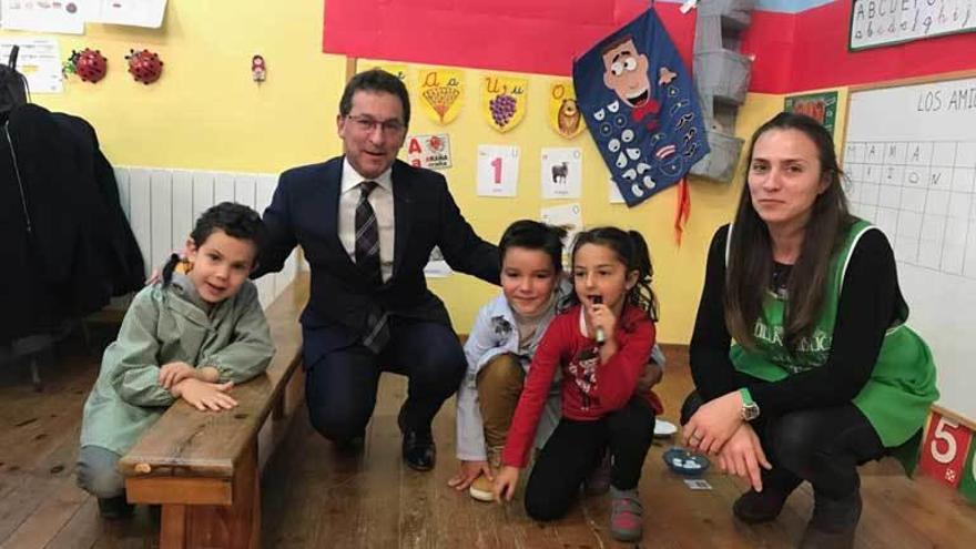 Genaro Alonso, junto a varios niños y una profesora en la escuela de Cue, ayer.