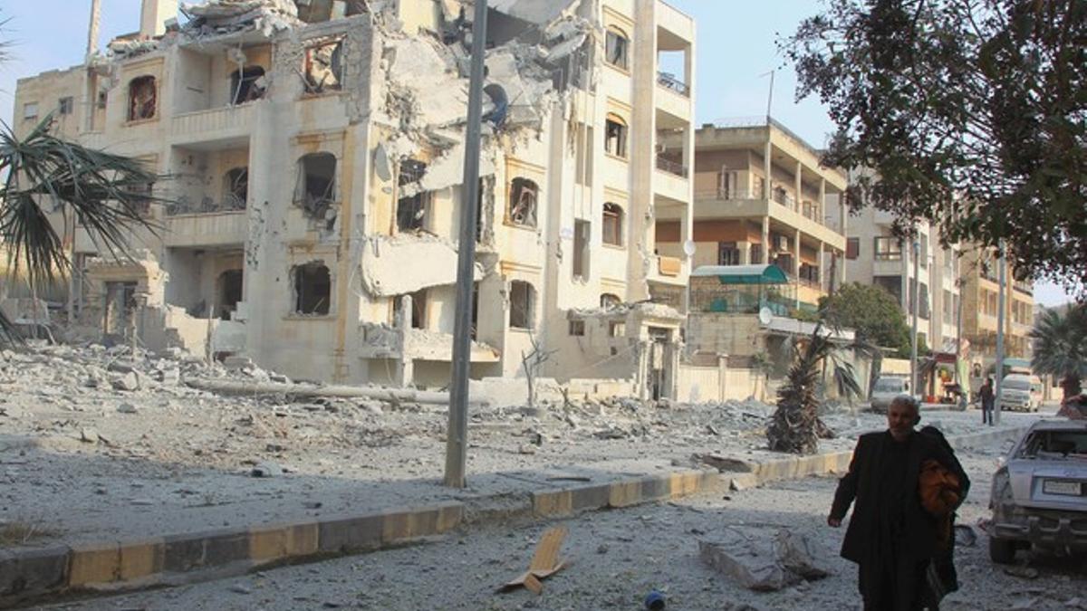 Un hombre camina junto a edificios dañados supuestamente durante ataques aéreos de aviones rusos contra Idleb.