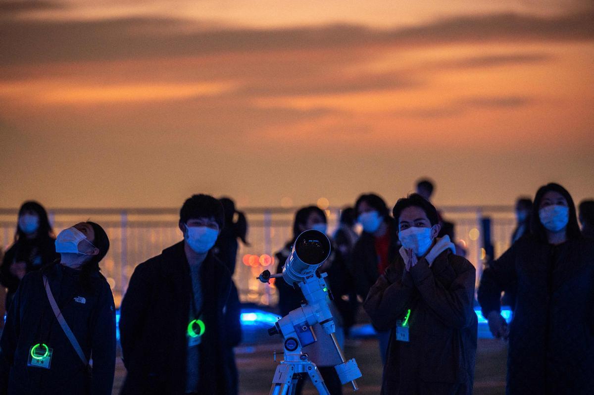 Un grupo de gente se reúne en la plataforma de observación de las colinas de Roppongi, en Tokio, para observar el eclipse parcial de luna.