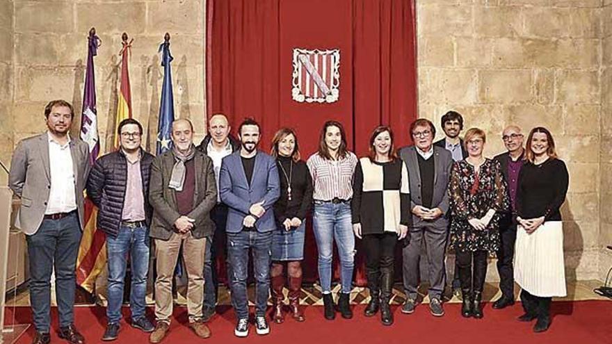 Cata Coll, con camisa a rayas, posa en el Consolat de Mar junto a Francina Armengol.