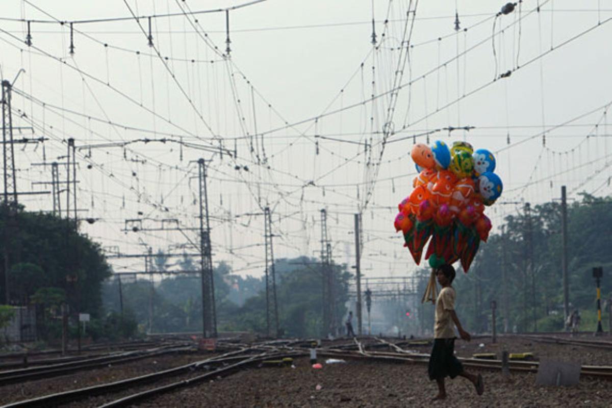 Un venedor de globus camina sobre una via fèrria a prop de l’estació Manggarai, a Jakarta (Indonèsia).