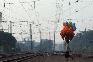 Un venedor de globus camina sobre una via fèrria a prop de l’estació Manggarai, a Jakarta (Indonèsia).