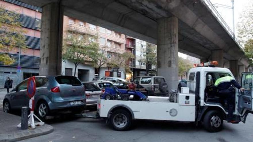 Una grua retira un cotxe a sota del viaducte.