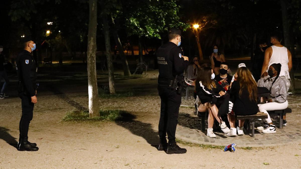 Varios policías inspeccionan a un grupo de jóvenes.