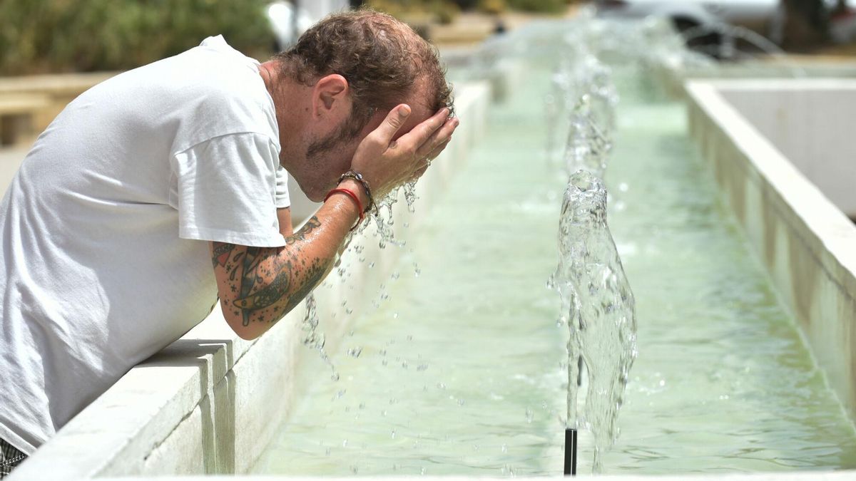 Un hombre se refresca en una fuente ante las altas temperaturas.