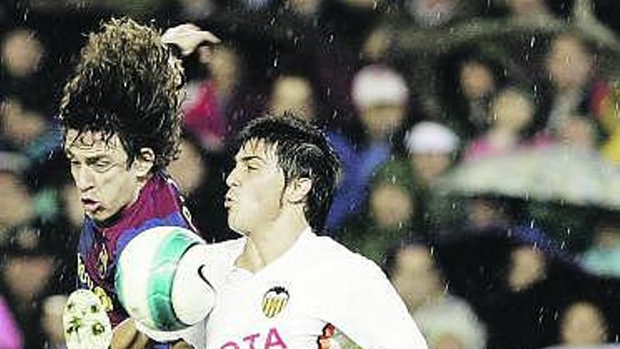 Villa disputa un balón a Puyol durante un Valencia-Barcelona.