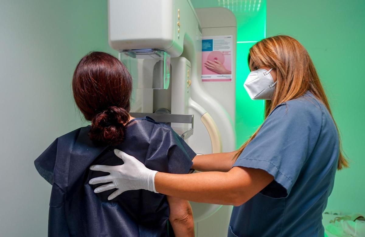 Una paciente con ayuda de una enfermera se hace una mamografía.