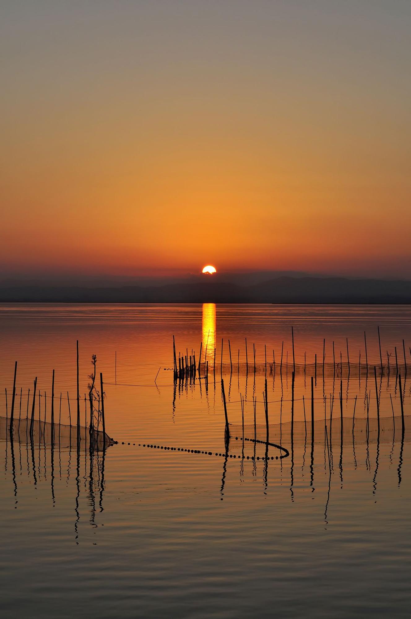 El sol se posa sobre el agua del Parque Natural de la Albufera de Valencia