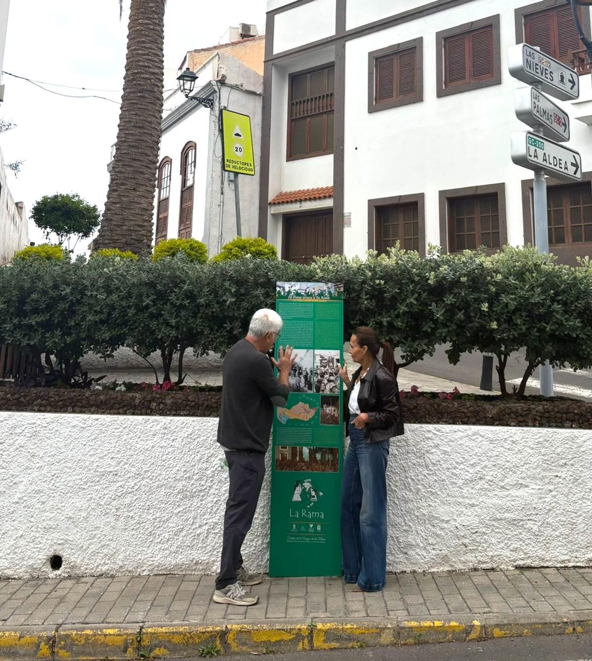 Valentín Barroso y María del Carmen Rosario junto a uno de los carteles explicativos de la fiesta de La Rama de Agaete.