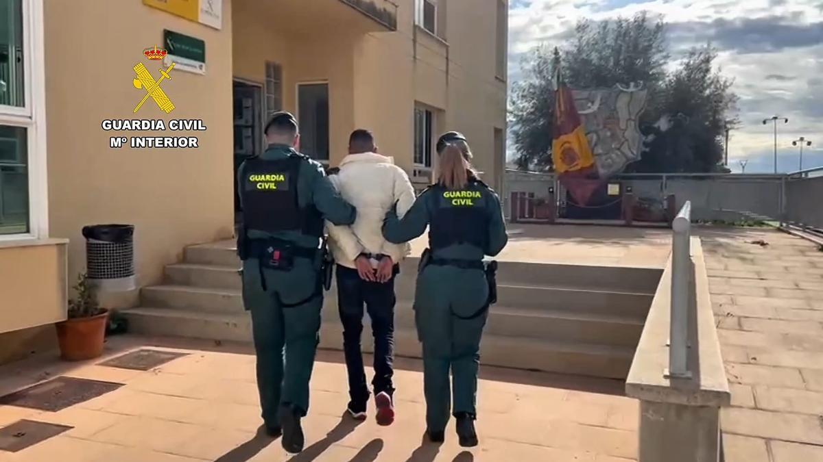 Dos guardias civiles trasladan a uno de los detenidos.