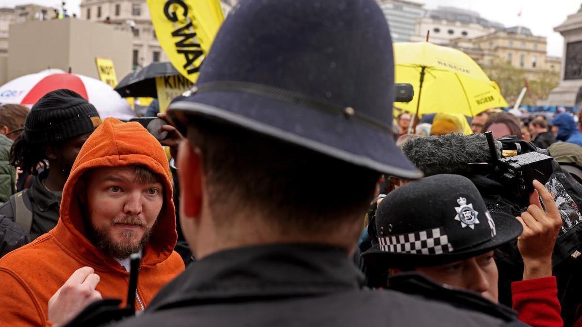 Un hombre habla con un policía durante la protesta de antimonárquicos en el día de la coronación de Carlos III.