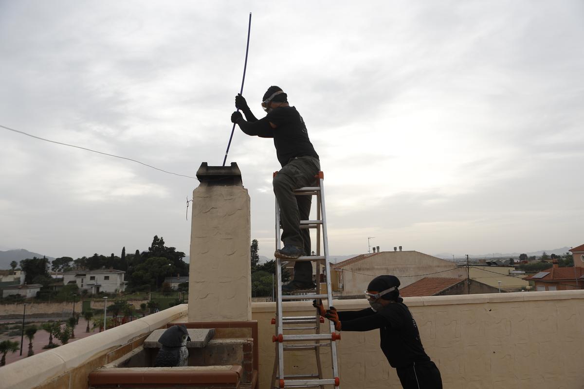 Dos trabajadores de la empresa Tu Deshollinador limpian una chimenea en una vivienda de Cartagena