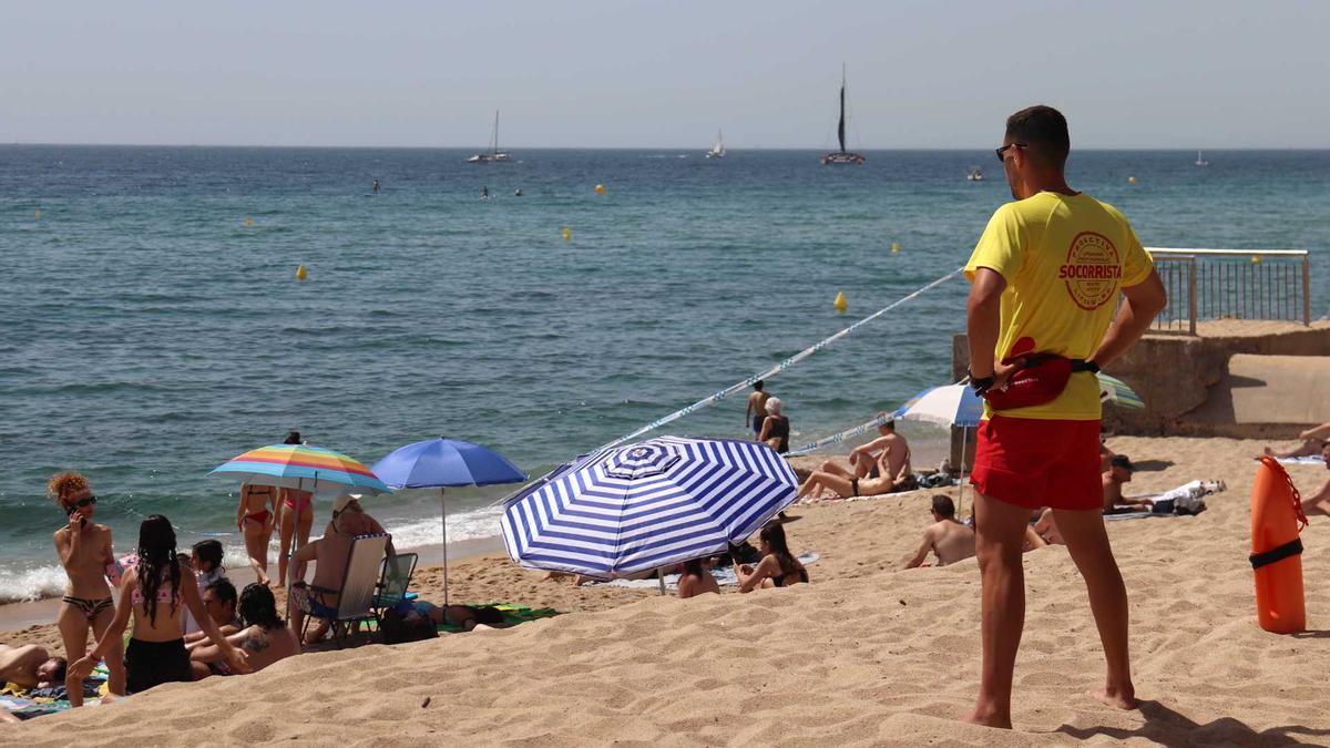 Un socorrista vigila els banyistes que omplen la platja del Pont d&#039;en Botifarreta de Badalona en plena onada de calor