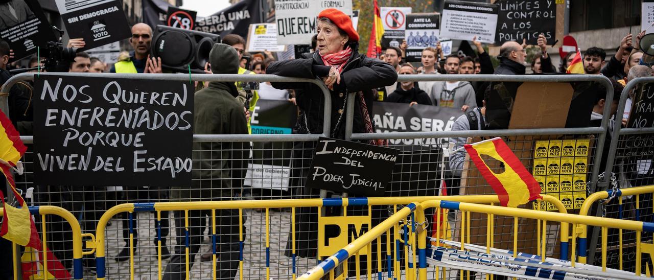 Una manifestante se sujeta sobre una valla durante las protestas en el Congreso de los Diputados.