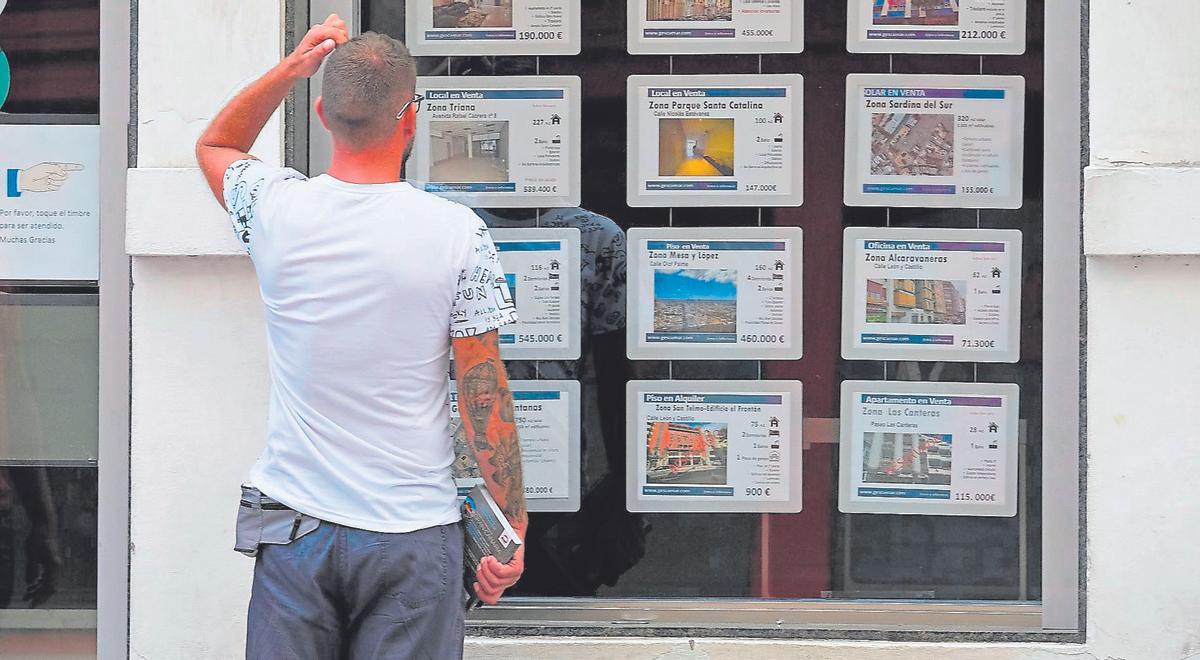 Un hombre mira el escaparate de una inmobiliaria en Canarias.