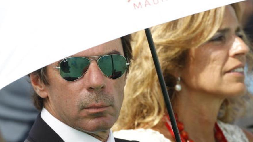 Aznar, junto con su esposa Ana Botella, cubiertos por un paraguas, durante una misa que el Papa ofreció en Madrid.