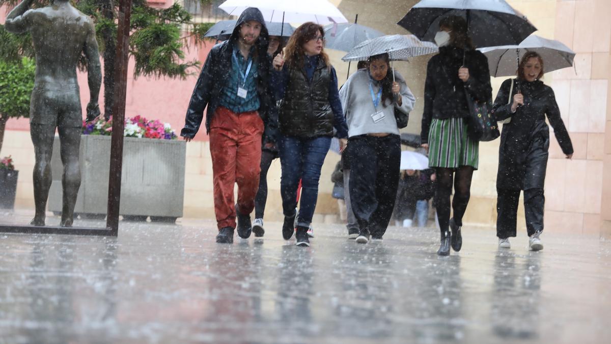 Varias personas caminando bajo la lluvia en Elche.