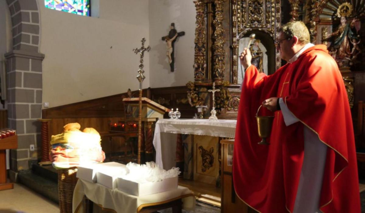 El párroco durante la misa en honor a San Blas, bendiciendo las pastas y bollas. | E. P.